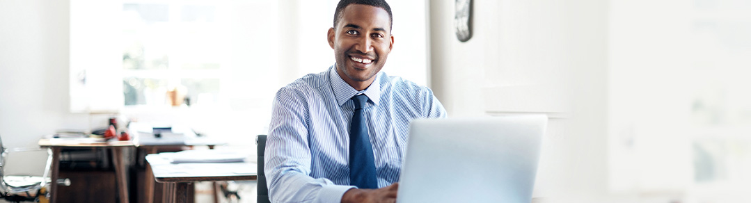 Man sitting in front of a laptop and smiling.