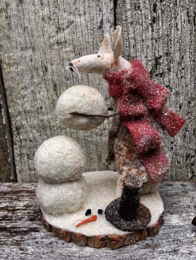 sculpture piece on wood shelf in front of wood fence.