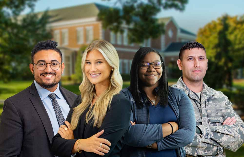 Four people standing and smiling with the university campus in the background.